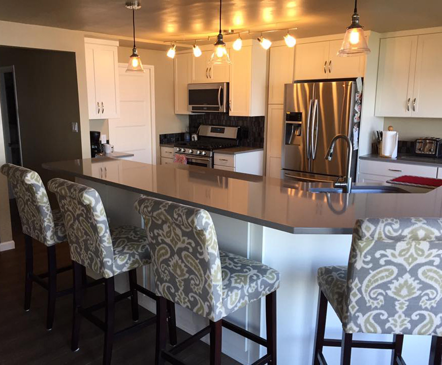 Example of a mid-sized transitional l-shaped open concept kitchen design in Seattle with an undermount sink, shaker cabinets, white cabinets, quartzite countertops, metallic backsplash, glass tile backsplash, stainless steel appliances and an island