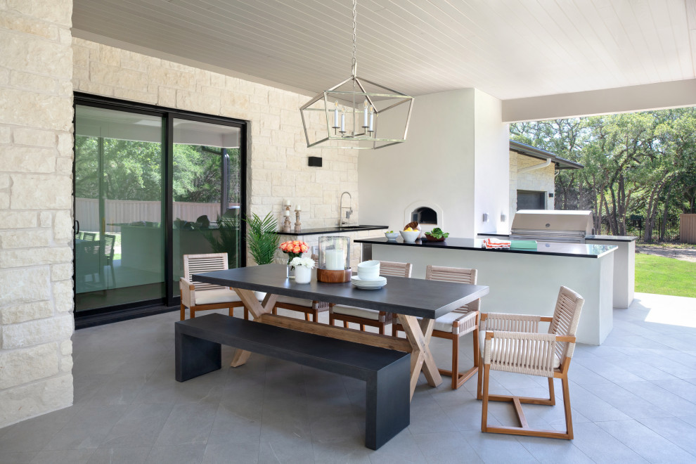 Cette photo montre une grande terrasse arrière chic avec une cuisine d'été, des pavés en béton et une extension de toiture.