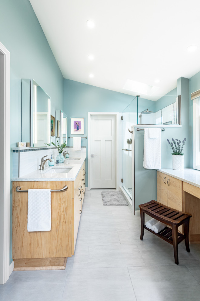 Idée de décoration pour une grande salle de bain principale design en bois clair avec un carrelage blanc, un mur bleu, un sol gris, un plan de toilette blanc, meuble double vasque, meuble-lavabo encastré, un placard à porte plane, un bidet, des carreaux de céramique, un sol en carrelage de céramique, un lavabo encastré, un plan de toilette en quartz modifié, une cabine de douche à porte battante, une niche et un plafond voûté.