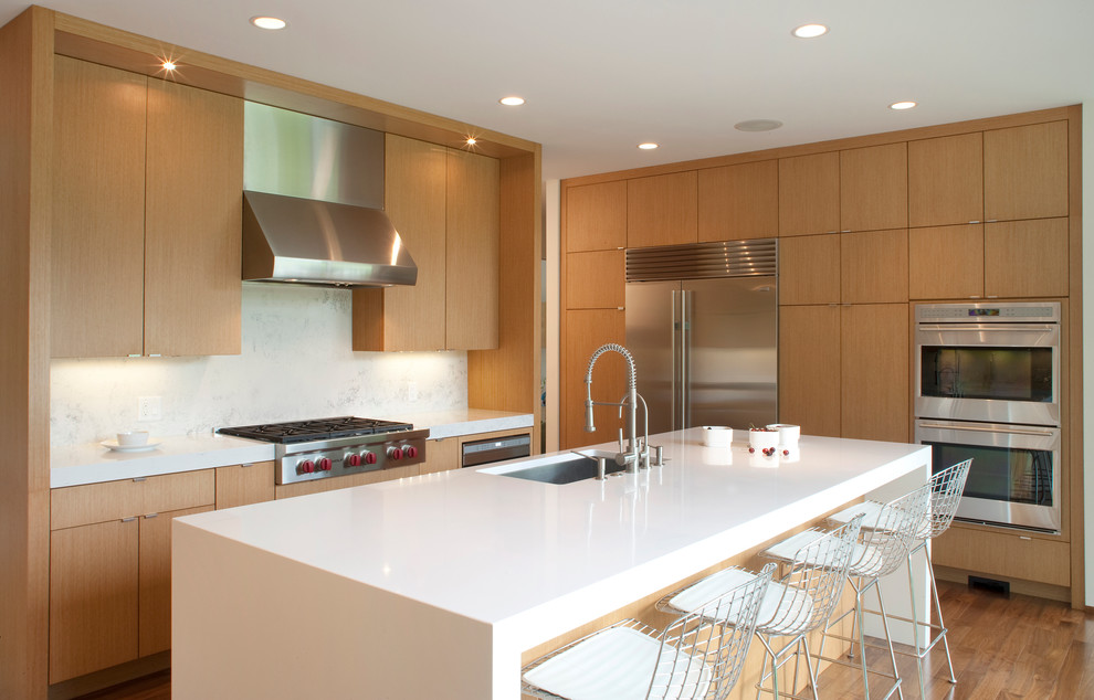 Inspiration for a contemporary galley kitchen in Milwaukee with an undermount sink, flat-panel cabinets, light wood cabinets, quartzite benchtops, white splashback, stone slab splashback and stainless steel appliances.
