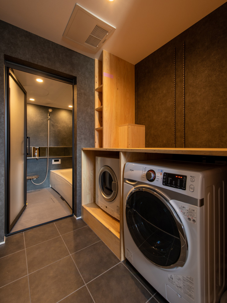 Inspiration for a small scandinavian dedicated laundry room in Other with flat-panel cabinets, black cabinets, grey walls, wallpaper, ceramic floors, a side-by-side washer and dryer, black floor and wallpaper.