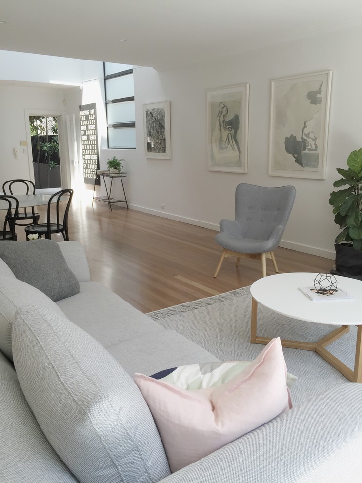 Photo of a large scandinavian open concept living room in Sydney with white walls, light hardwood floors, a freestanding tv and beige floor.
