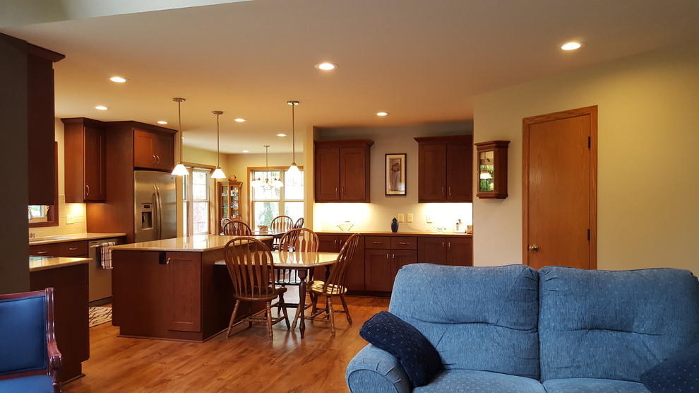 Inspiration for a large transitional l-shaped vinyl floor eat-in kitchen remodel with an undermount sink, shaker cabinets, dark wood cabinets, quartz countertops, beige backsplash, subway tile backsplash, stainless steel appliances and an island