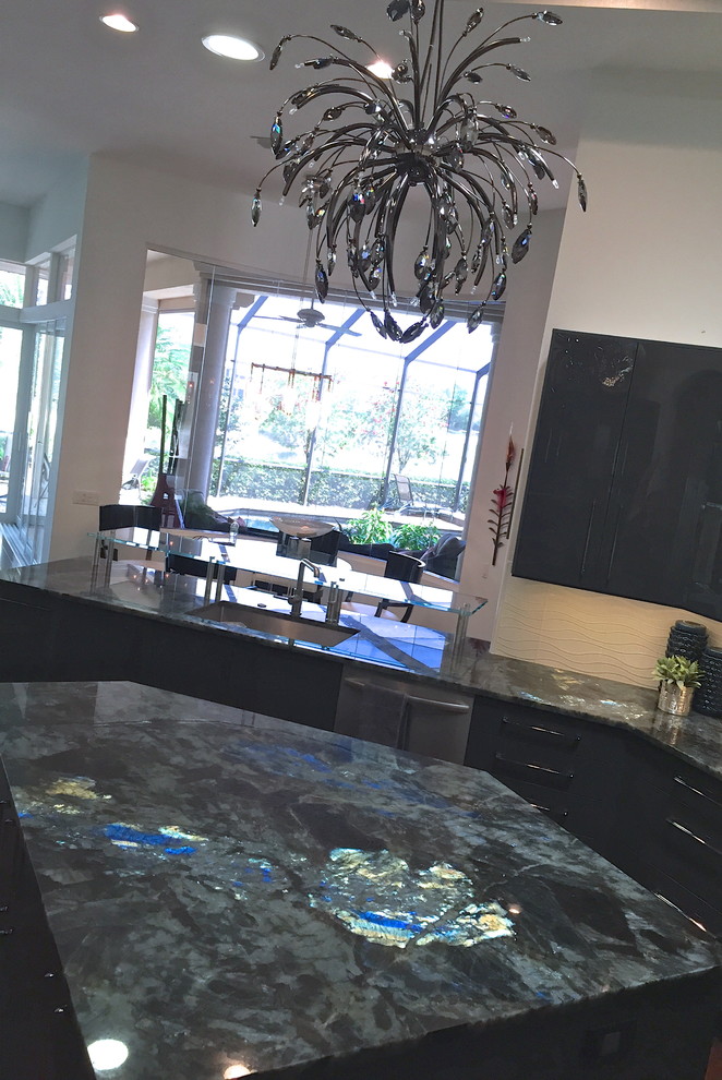 Photo of a large contemporary u-shaped eat-in kitchen in Miami with granite benchtops, white splashback, glass tile splashback, stainless steel appliances, dark hardwood floors, an undermount sink, glass-front cabinets, black cabinets and with island.