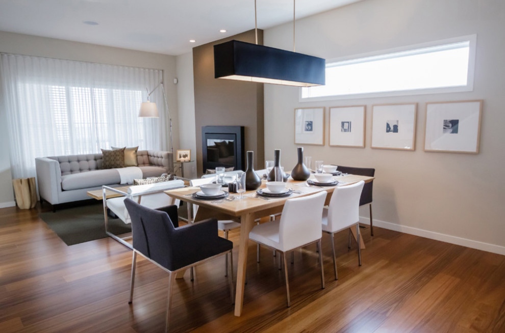 Mid-sized contemporary open plan dining in New York with beige walls, medium hardwood floors, a hanging fireplace, a plaster fireplace surround and brown floor.