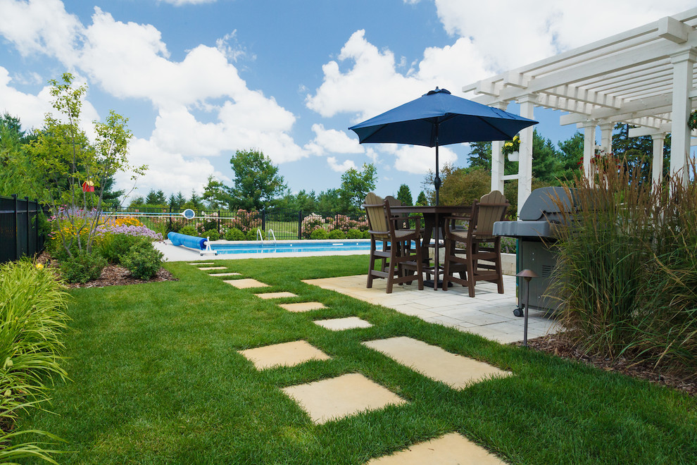 Photo of a mid-sized traditional backyard rectangular pool in Milwaukee with concrete slab.