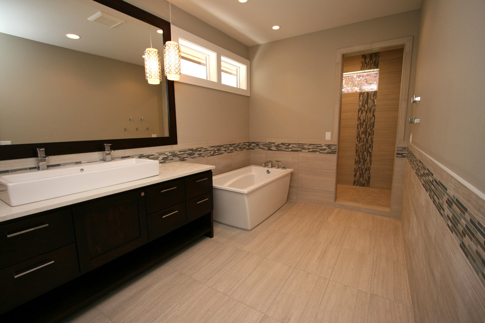 This is an example of a mid-sized contemporary master bathroom in Seattle with a vessel sink, shaker cabinets, dark wood cabinets, engineered quartz benchtops, a freestanding tub, an alcove shower, a one-piece toilet, beige tile, porcelain tile, grey walls and porcelain floors.