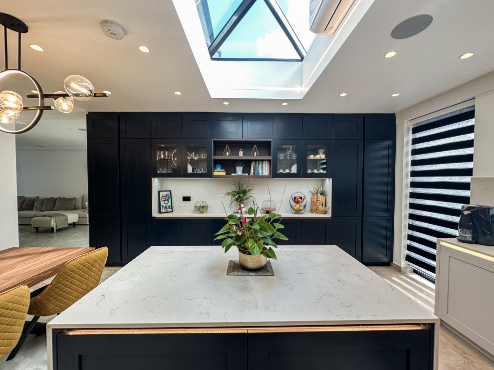 Inspiration for a large classic l-shaped kitchen/diner in London with a built-in sink, shaker cabinets, blue cabinets, quartz worktops, white splashback, engineered quartz splashback, integrated appliances, porcelain flooring, an island, beige floors, white worktops and feature lighting.