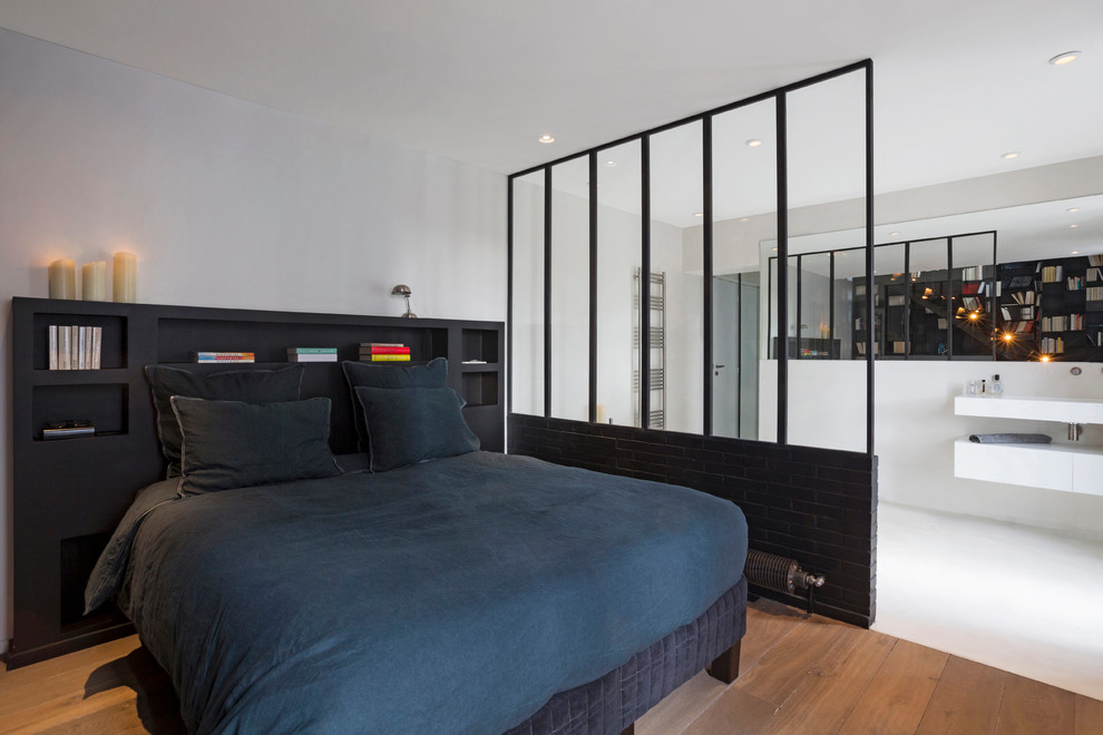 Mid-sized contemporary master bedroom in Paris with white walls, light hardwood floors and no fireplace.