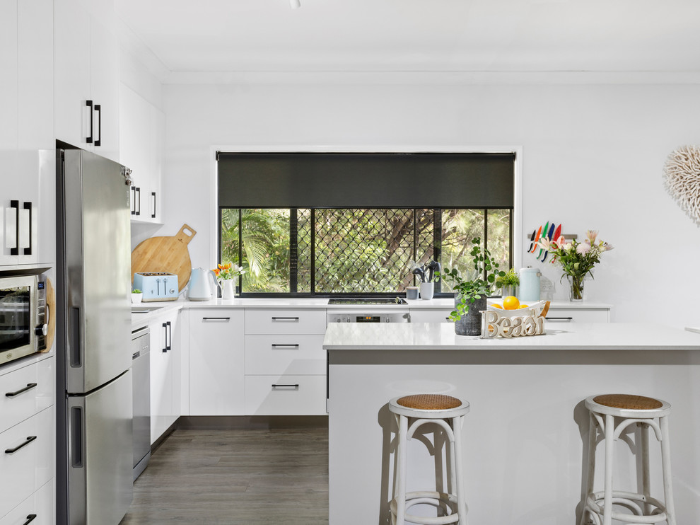 Photo of a mid-sized modern eat-in kitchen in Gold Coast - Tweed with flat-panel cabinets, white cabinets, quartz benchtops, ceramic splashback, with island and white benchtop.
