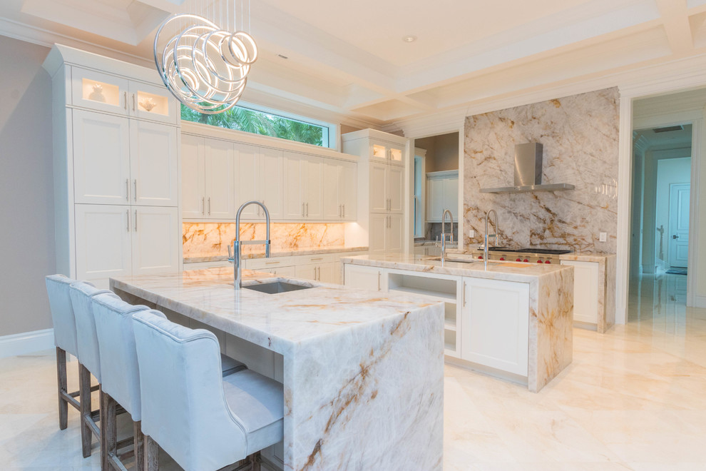 Example of a huge transitional u-shaped marble floor and white floor open concept kitchen design with an undermount sink, flat-panel cabinets, white cabinets, quartzite countertops, white backsplash, stone slab backsplash and two islands