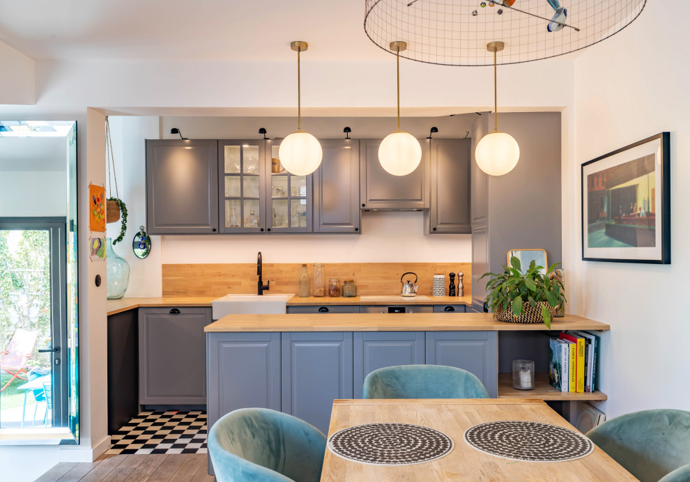 Moderne Wohnküche in U-Form mit unterschiedlichen Schrankstilen, grauen Schränken, Arbeitsplatte aus Holz, Rückwand aus Holz, Elektrogeräten mit Frontblende, Zementfliesen für Boden und Kücheninsel in Paris