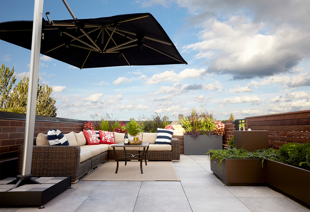 Photo of a large contemporary rooftop deck in Chicago with a container garden and an awning.