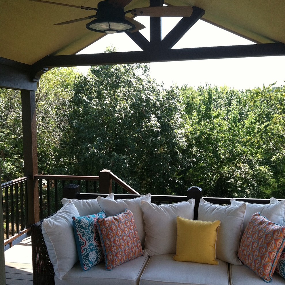 This is an example of a large country backyard deck in Kansas City with a roof extension.