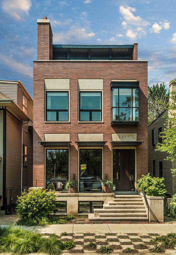 This is an example of a modern three-storey brick orange house exterior in Chicago with a flat roof, a metal roof and a black roof.