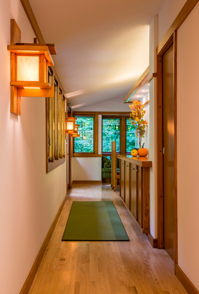 This is an example of a small arts and crafts hallway in Minneapolis with white walls, light hardwood floors and brown floor.