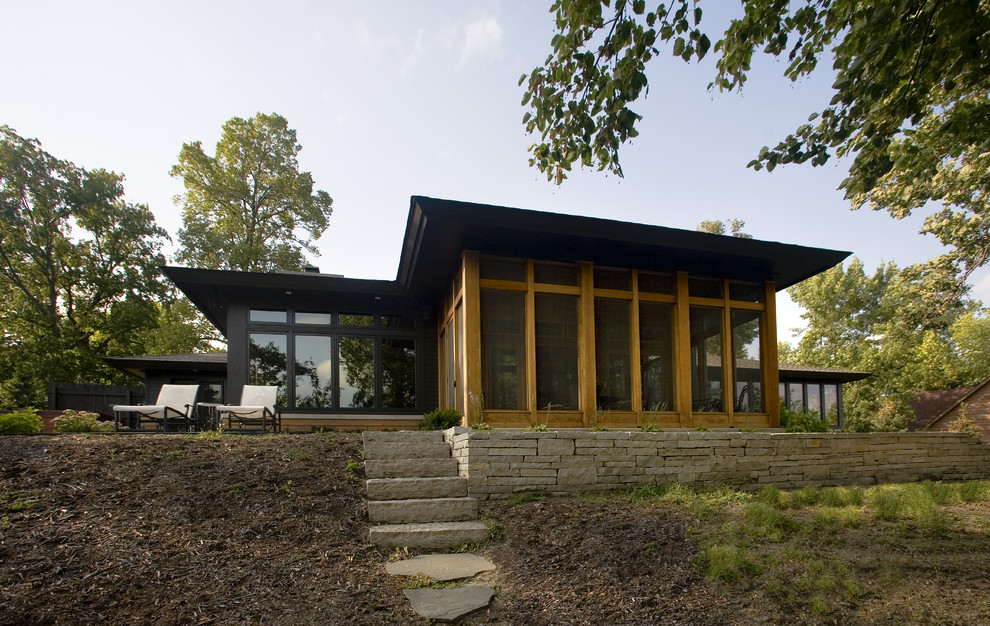 Large midcentury one-storey black exterior in Minneapolis with mixed siding and a hip roof.