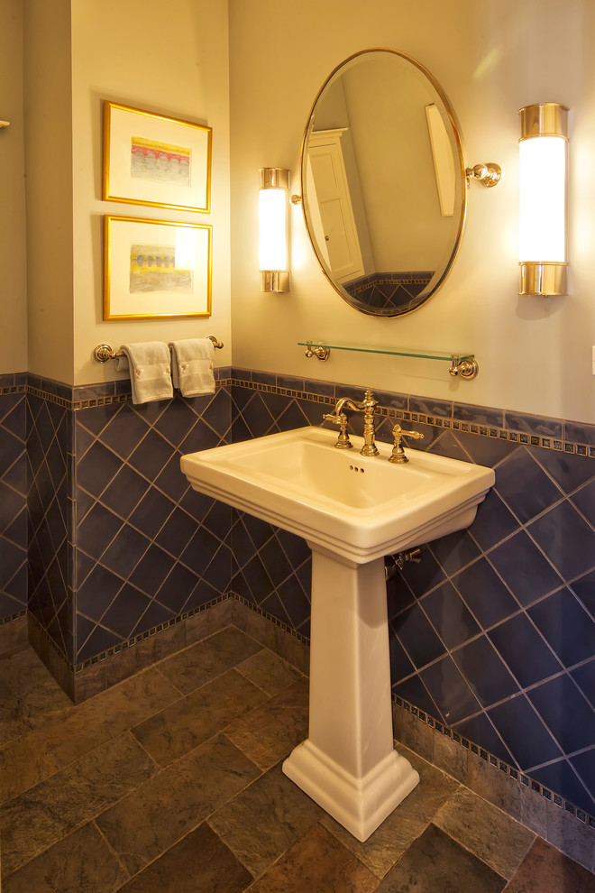 This is an example of a traditional powder room in New York with a one-piece toilet, blue tile and a pedestal sink.