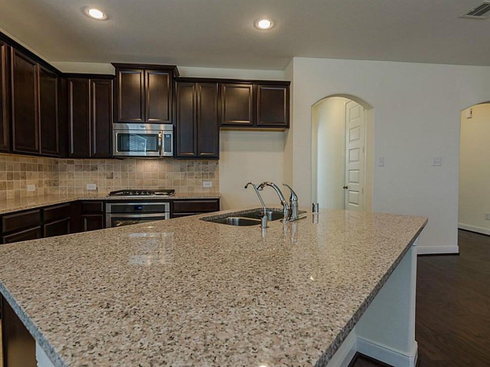 Inspiration for a mid-sized transitional l-shaped dark wood floor open concept kitchen remodel with a double-bowl sink, raised-panel cabinets, dark wood cabinets, beige backsplash, stainless steel appliances and an island
