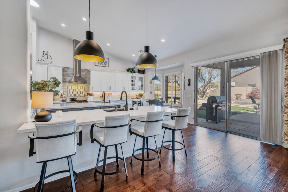Design ideas for a large transitional u-shaped kitchen in Phoenix with an undermount sink, flat-panel cabinets, grey cabinets, quartz benchtops, grey splashback, marble splashback, stainless steel appliances, medium hardwood floors, with island, brown floor, white benchtop and vaulted.