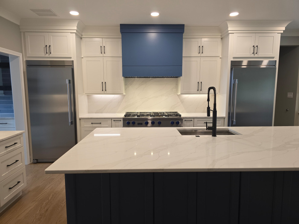 Kitchen - large modern l-shaped medium tone wood floor and brown floor kitchen idea with an undermount sink, shaker cabinets, white cabinets, quartz countertops, gray backsplash, subway tile backsplash, stainless steel appliances, an island and white countertops