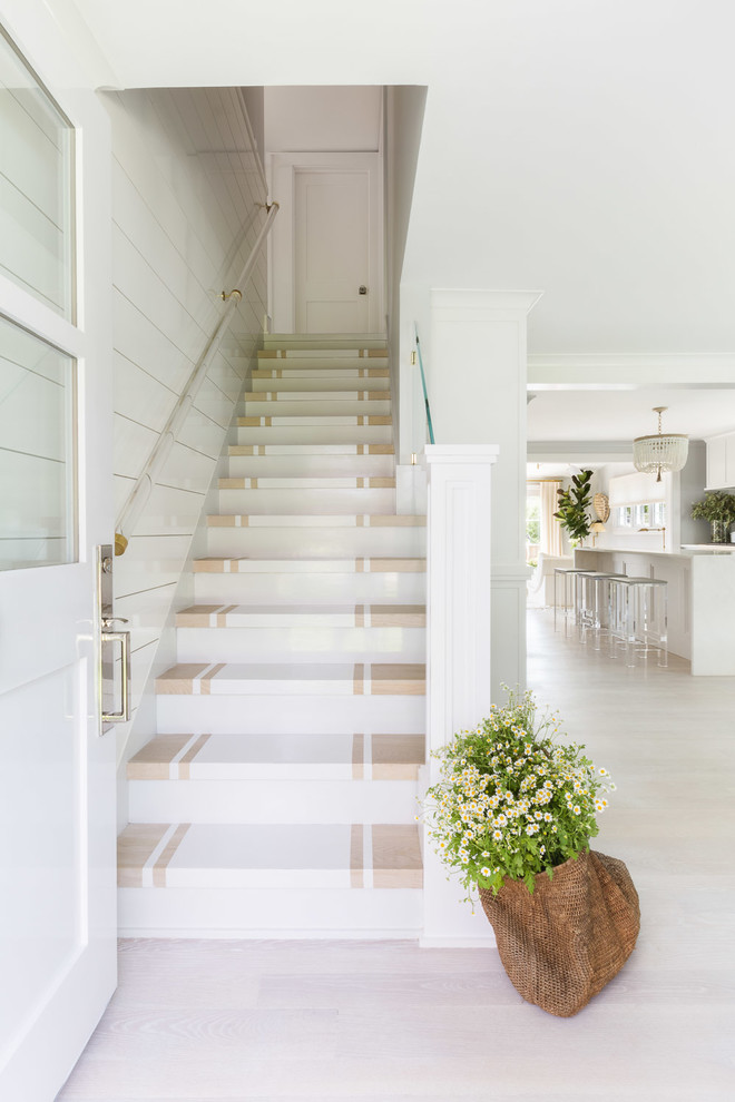 This is an example of a beach style painted wood straight staircase in New York with painted wood risers.