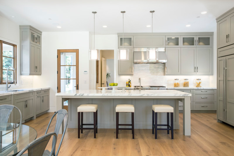 Inspiration for a huge contemporary u-shaped medium tone wood floor eat-in kitchen remodel in San Francisco with a drop-in sink, shaker cabinets, green cabinets, marble countertops, yellow backsplash, stone tile backsplash and paneled appliances