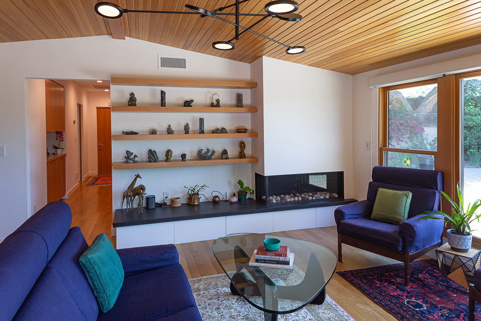 Midcentury open concept living room in Los Angeles with white walls, light hardwood floors, a corner fireplace, a plaster fireplace surround, no tv, brown floor and wood.