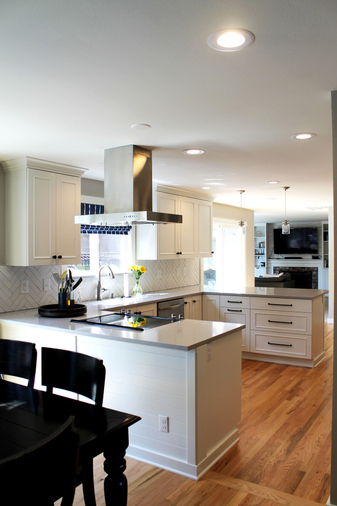Example of a mid-sized transitional u-shaped medium tone wood floor eat-in kitchen design in Seattle with an undermount sink, shaker cabinets, white cabinets, quartz countertops, white backsplash, ceramic backsplash, stainless steel appliances, a peninsula and gray countertops