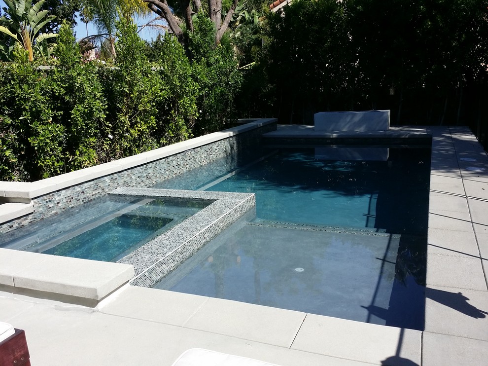 Photo of a mid-sized modern backyard rectangular pool in Los Angeles with a water feature and concrete pavers.