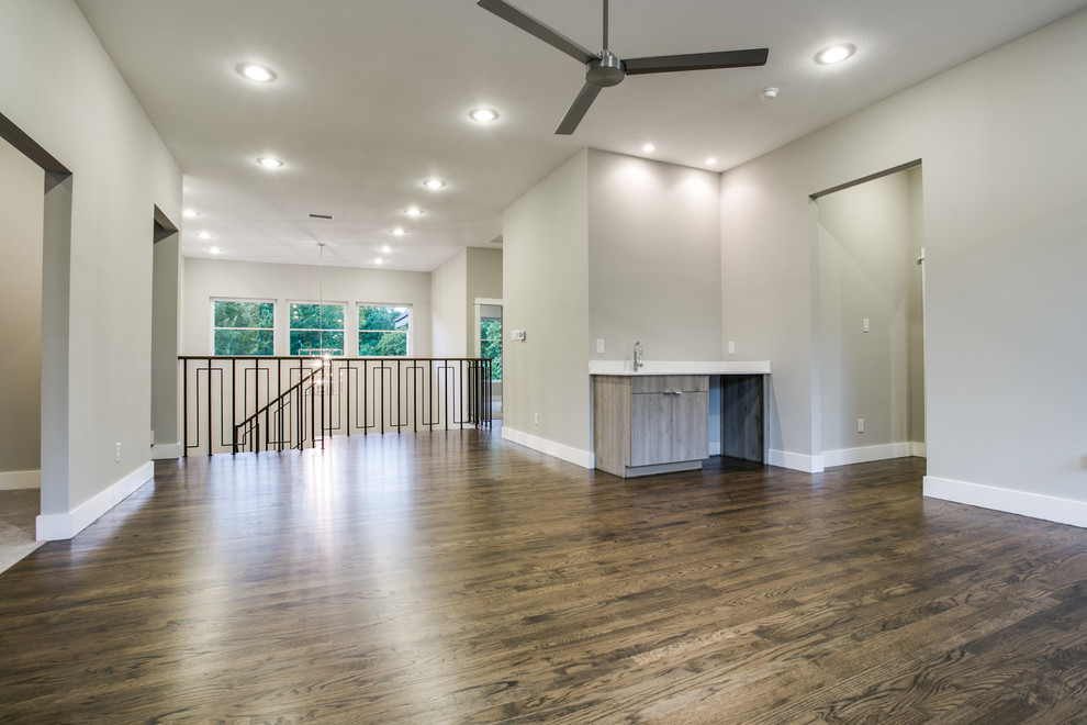 This is an example of a large modern open concept family room in Dallas with a game room, beige walls, dark hardwood floors, no fireplace, a wall-mounted tv, brown floor and vaulted.