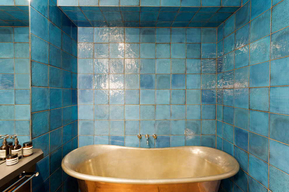 Photo of a mid-sized eclectic master bathroom in Melbourne with dark wood cabinets, a freestanding tub, an alcove shower, a one-piece toilet, blue tile, ceramic tile, blue walls, porcelain floors, an undermount sink and limestone benchtops.