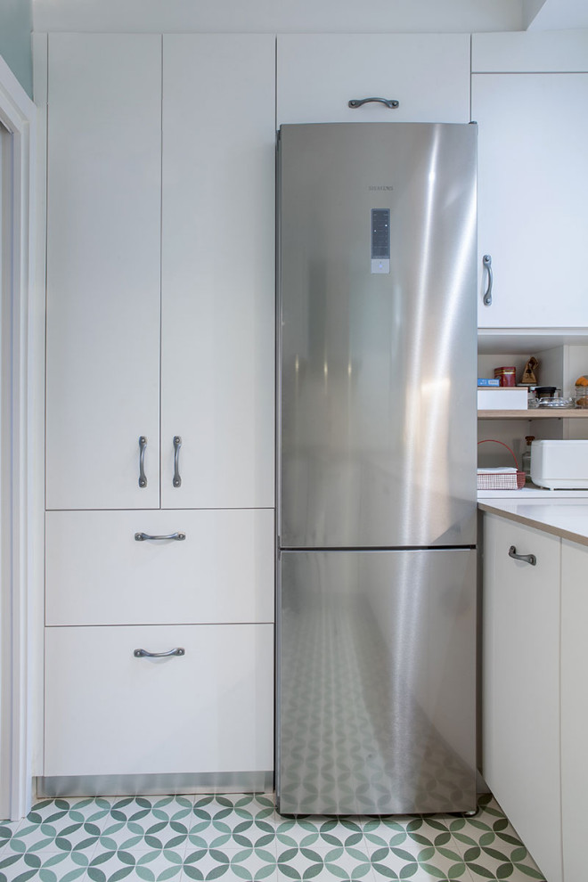 Immagine di una piccola cucina a L minimal con lavello a vasca singola, ante lisce, ante bianche, elettrodomestici in acciaio inossidabile, pavimento verde e top beige