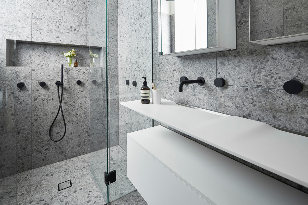 Mid-sized contemporary master bathroom in Melbourne with white cabinets, a double shower, a wall-mount toilet, gray tile, stone slab, grey walls, terrazzo floors, a wall-mount sink, laminate benchtops, grey floor, a hinged shower door, white benchtops and furniture-like cabinets.