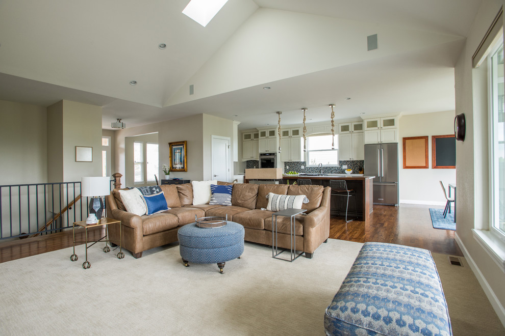 This is an example of a large beach style open concept family room in Denver with beige walls, carpet, a standard fireplace, a tile fireplace surround, a wall-mounted tv and beige floor.