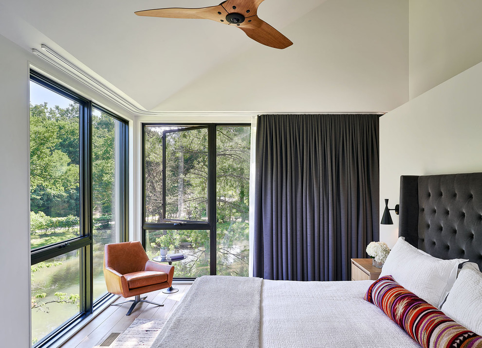 Photo of a contemporary bedroom in Kansas City with white walls, light hardwood floors, no fireplace and brown floor.
