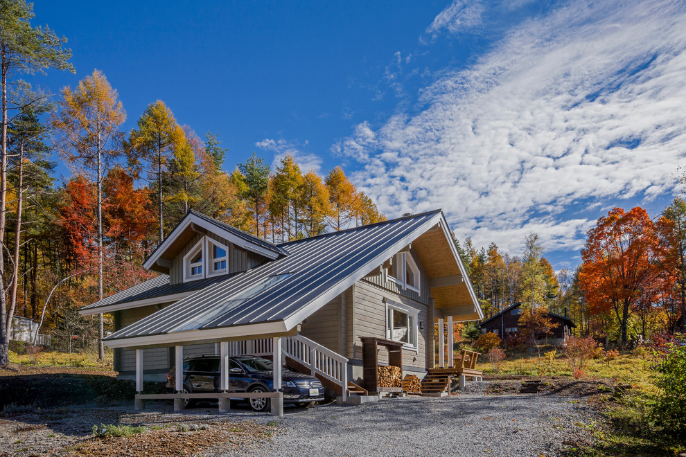 Foto della facciata di una casa grigia con rivestimento in legno, tetto grigio e tetto a capanna