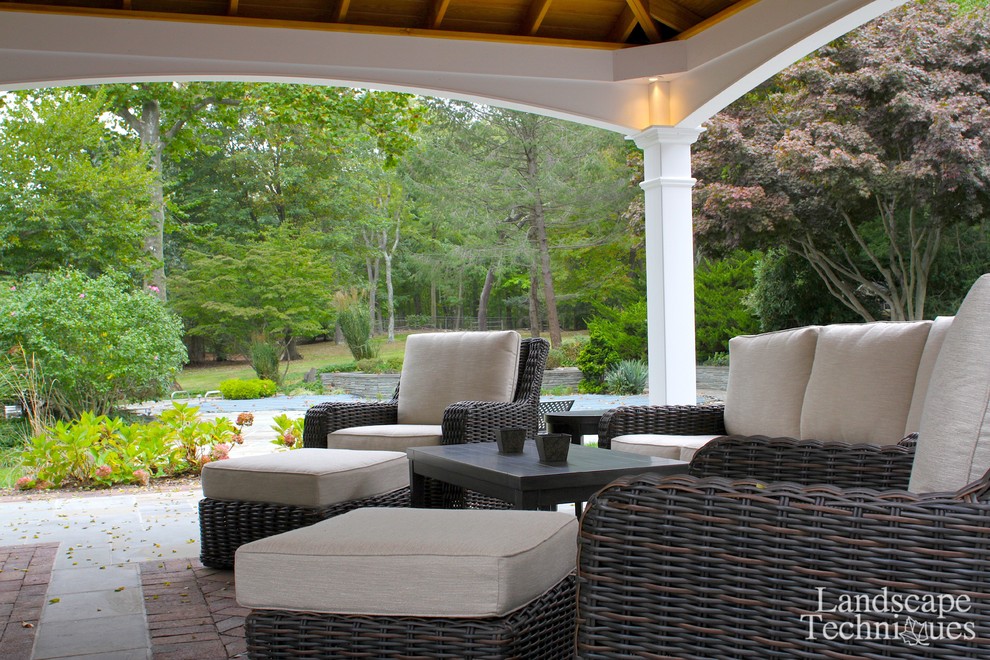 Large country backyard patio in New York with a fire feature, natural stone pavers and a gazebo/cabana.