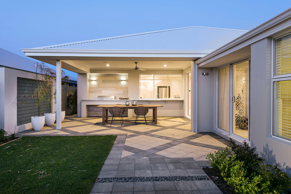 This is an example of a large beach style backyard patio in Perth with concrete pavers and a roof extension.