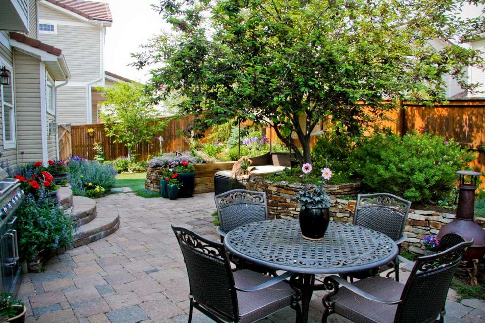 This is an example of a small rustic partial sun backyard concrete paver retaining wall landscape in Denver.