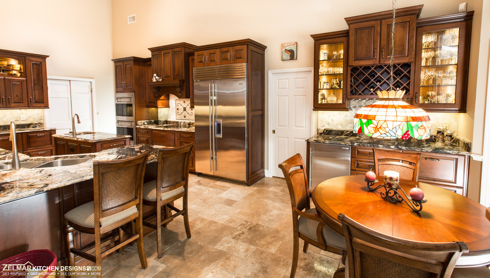 Photo of a large traditional u-shaped eat-in kitchen in Orlando with an undermount sink, raised-panel cabinets, medium wood cabinets, granite benchtops, beige splashback, stone tile splashback, travertine floors and with island.