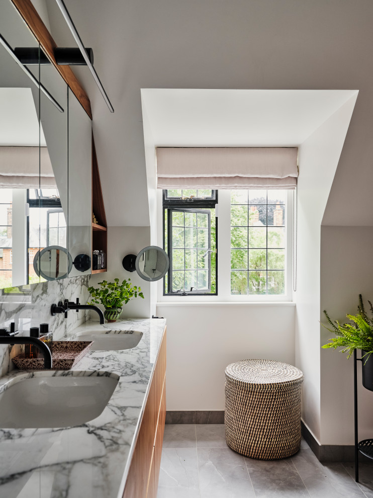 Cette image montre une salle de bain traditionnelle avec un placard à porte plane, des portes de placard marrons, un sol en carrelage de porcelaine, un lavabo encastré, un plan de toilette en marbre, un sol gris, meuble double vasque et meuble-lavabo suspendu.