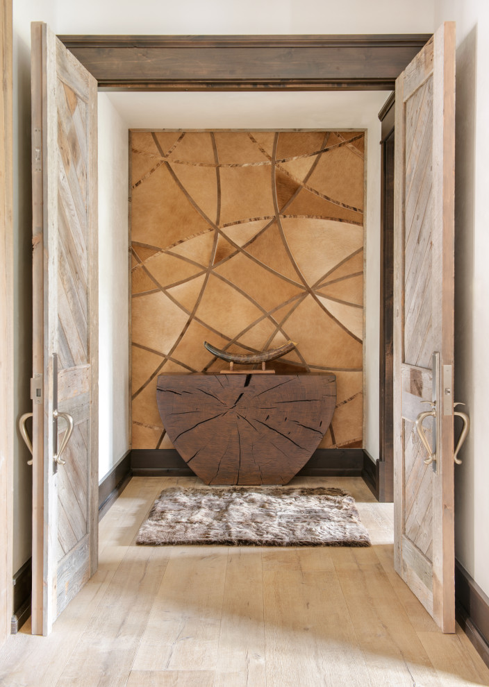 Example of a large mountain style light wood floor and brown floor entry hall design with beige walls and a light wood front door