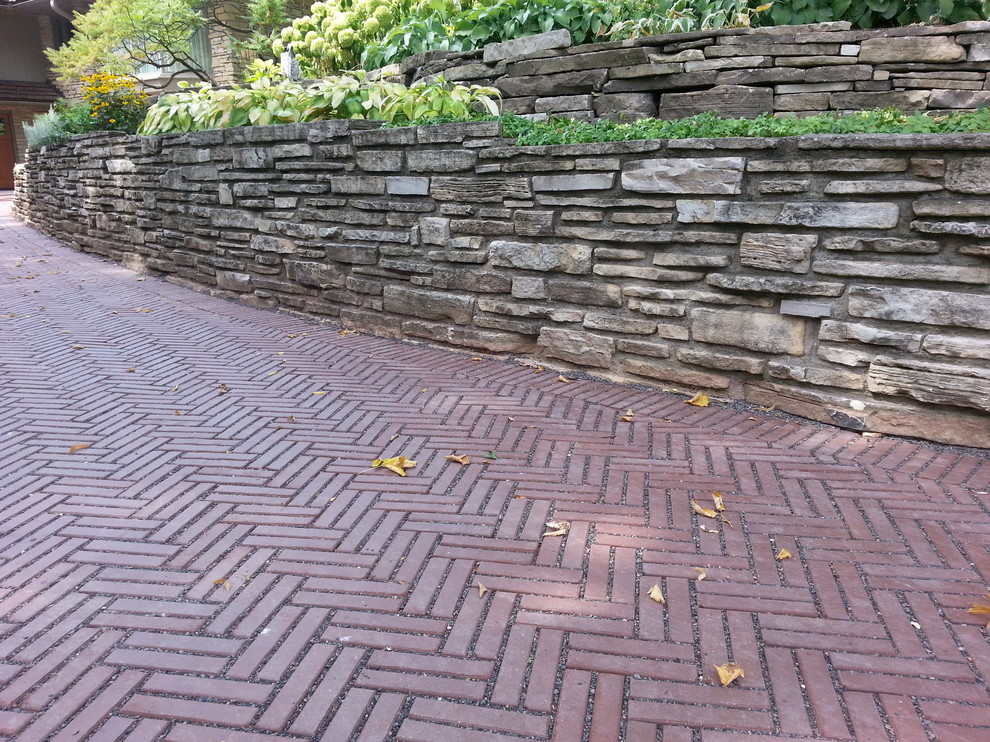 This is an example of a mid-sized country front yard shaded driveway for summer in Cleveland with brick pavers.