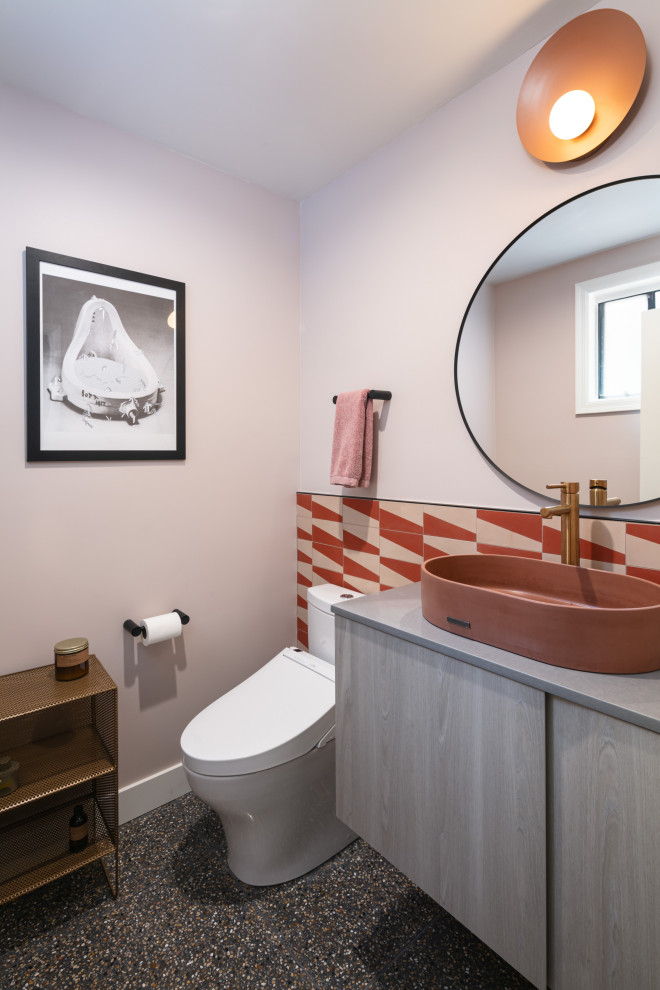 Inredning av ett modernt litet grå grått toalett, med släta luckor, skåp i ljust trä, en bidé, röd kakel, cementkakel, rosa väggar, terrazzogolv, ett fristående handfat, bänkskiva i kvarts och svart golv