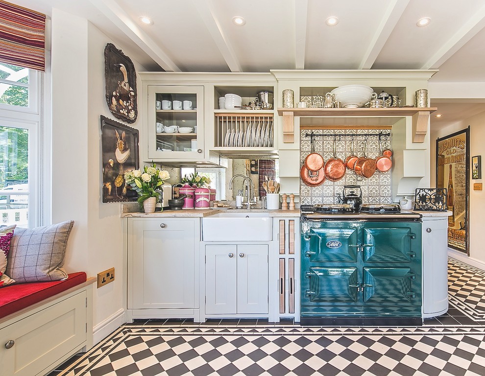 This is an example of a mid-sized traditional u-shaped eat-in kitchen in Berkshire with a farmhouse sink, shaker cabinets, grey cabinets, limestone benchtops, metallic splashback, glass sheet splashback, coloured appliances, porcelain floors and no island.