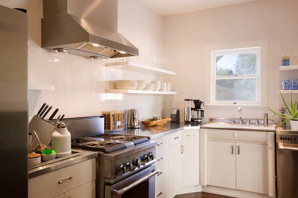 Transitional enclosed kitchen photo in Austin with flat-panel cabinets, white cabinets, stainless steel countertops, white backsplash and stainless steel appliances