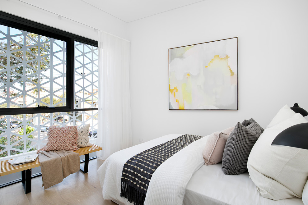 This is an example of a contemporary guest bedroom in Sydney with white walls, light hardwood floors, no fireplace and brown floor.