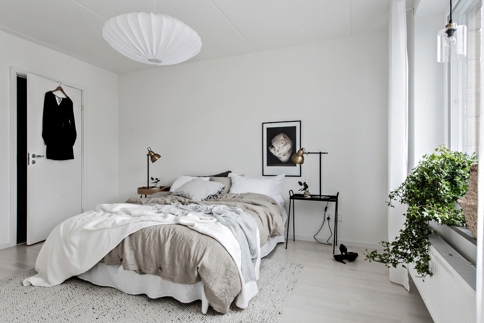 Mid-sized scandinavian bedroom in Gothenburg with white walls, light hardwood floors and beige floor.