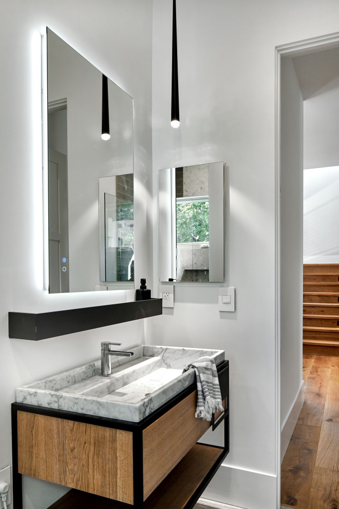 Aménagement d'un WC et toilettes contemporain en bois clair de taille moyenne avec un placard à porte plane, un mur blanc, un lavabo intégré, un plan de toilette en marbre, un plan de toilette gris et meuble-lavabo sur pied.